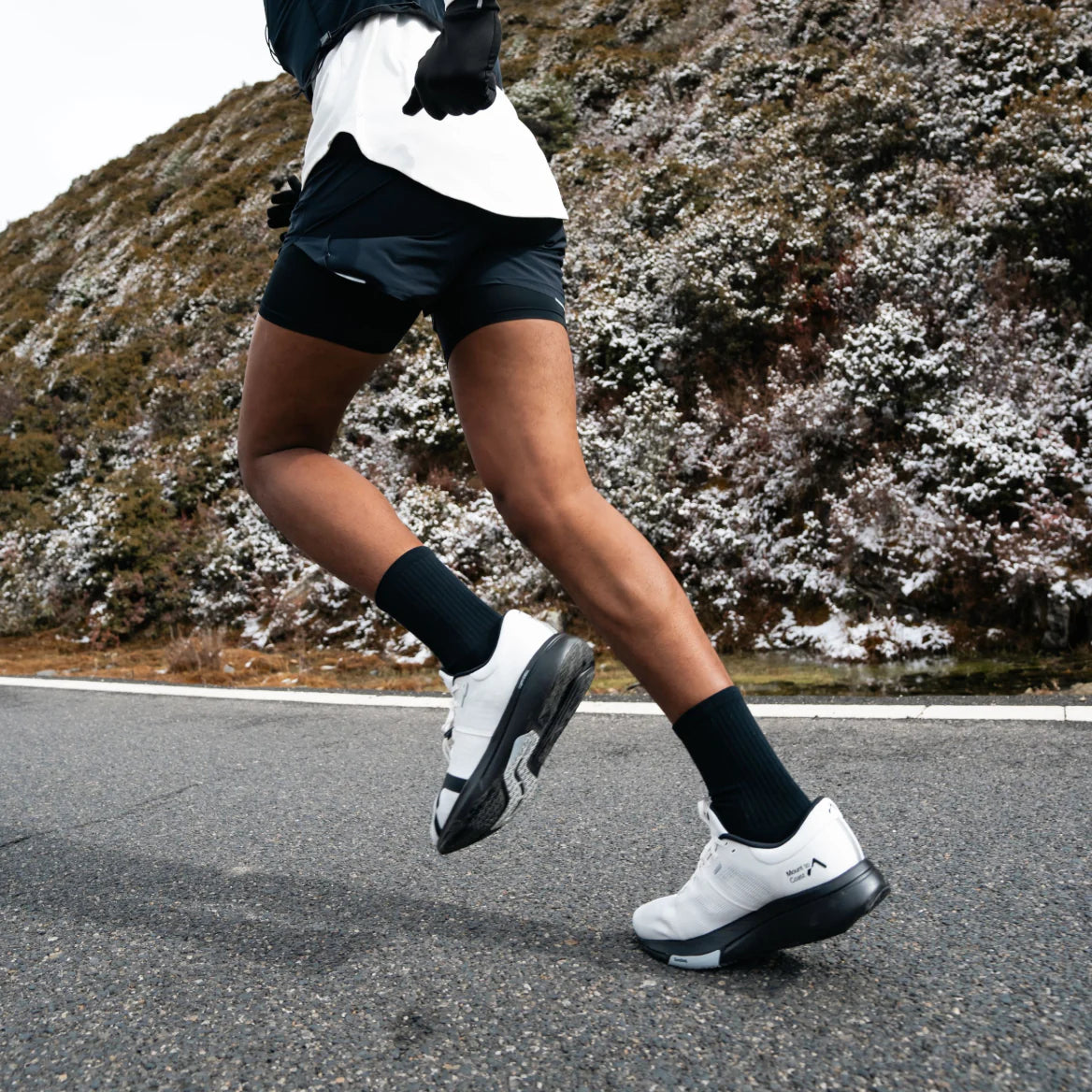 Runner wearing Mount to Coast R1 running shoes on road #Color_white|black